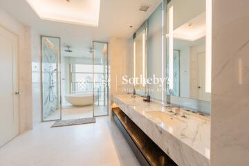 Modern bathroom with double sinks, large mirrors, a bathtub, and a shower