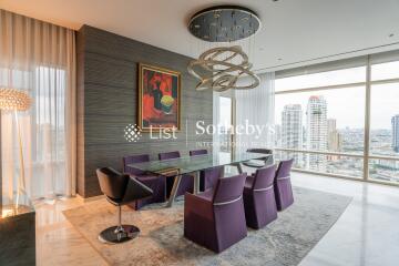 Modern dining area with a large glass table, stylish chairs, and city view