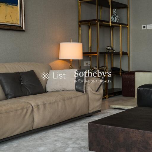 Living room with beige leather sofa and dark cushions, a modern lamp, and a stylish shelving unit.