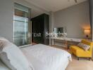 Modern bedroom with a large bed, a yellow chair, and a vanity table