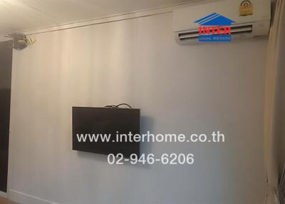 Living room with wall-mounted TV and air conditioning unit