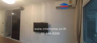 Living room with wall-mounted TV and air conditioning unit