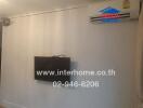 Living room with wall-mounted TV and air conditioning unit