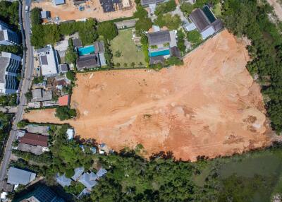 Aerial view of a large plot of land surrounded by houses and greenery