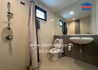 Modern bathroom with shower, toilet, sink, and large mirror