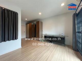 Bedroom with wooden floor, wardrobe, glass table, and black curtains