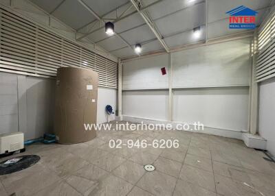 spacious indoor utility or storage room with protective roofing and a large water tank