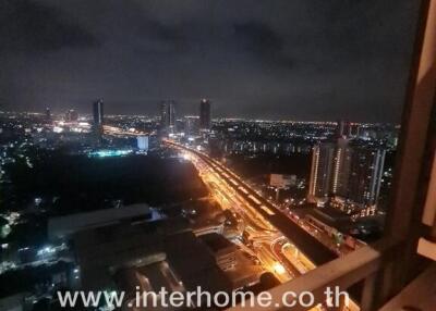 Night view of a cityscape from a balcony or window with visible traffic and high-rise buildings