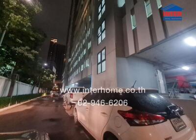 Exterior view of a building at nighttime with cars parked along the street