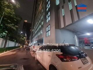 Exterior view of a building at nighttime with cars parked along the street