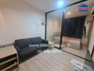 Living area with adjacent bedroom separated by glass partition, featuring a sofa, side table, and air conditioning.