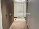 A hallway with built-in cupboards and a view of a doorway