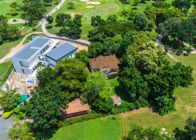 Aerial view of a property with a modern building and lush green surroundings