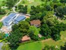 Aerial view of a property with a modern building and lush green surroundings