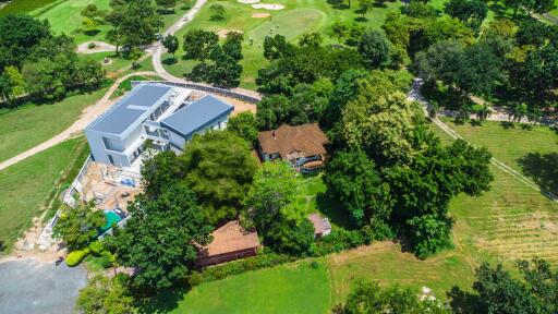 Aerial view of a property with a modern building and lush green surroundings