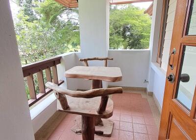 Rustic wooden furniture on a balcony with a view of greenery