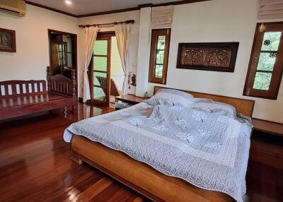 Spacious master bedroom with wooden floors and a large bed