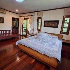 Spacious master bedroom with wooden floors and a large bed