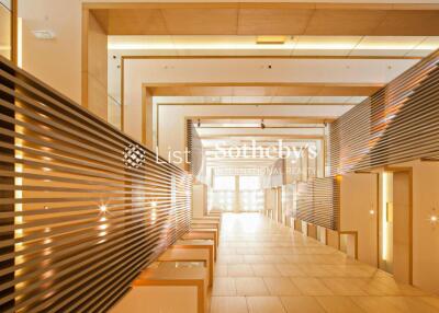 Modern building hallway with illuminated wooden paneling and tile flooring