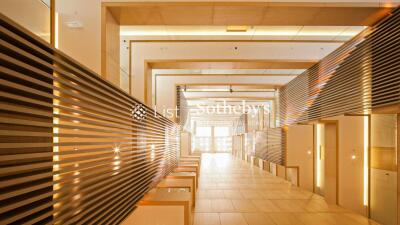 Modern building hallway with illuminated wooden paneling and tile flooring