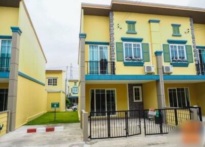 Exterior view of a yellow townhouse with green accents