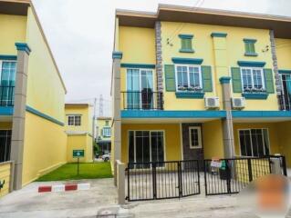 Exterior view of a yellow townhouse with green accents