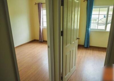 Bedroom with wooden floor and two windows with curtains