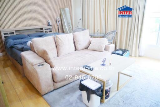 Cozy living area with beige sofa and adjoining bed