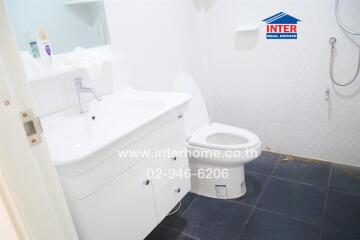 Modern bathroom with white fixtures and dark floor tiles