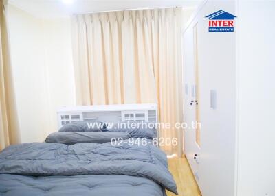 Small bedroom with a gray bedspread, white wardrobe, and beige curtains.