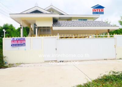 Two-story house with a white fence and gated driveway, featuring INTER Real Estate signage.