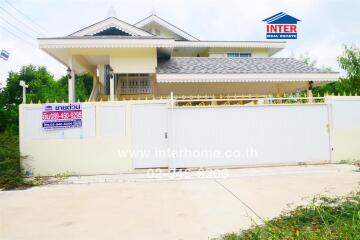 Two-story house with a white fence and gated driveway, featuring INTER Real Estate signage.