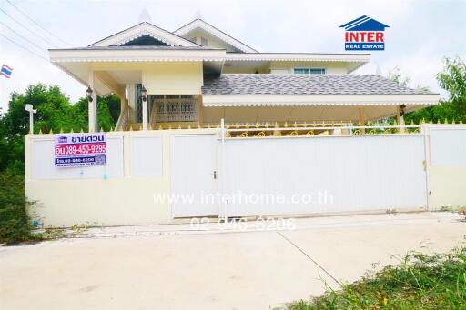 Two-story house with a white fence and gated driveway, featuring INTER Real Estate signage.