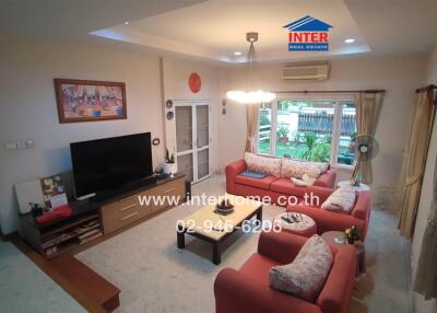 Modern living room with red sofas, TV, and large windows