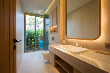 Modern bathroom with large mirror and vanity, glass shower door, and natural lighting