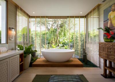 Modern bathroom with standalone tub and large window with garden view