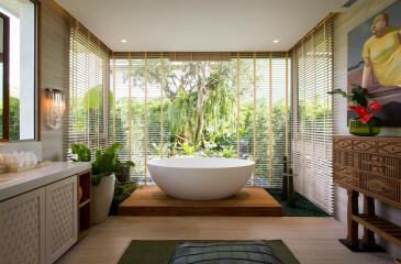 Modern bathroom with standalone tub and large window with garden view