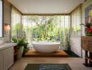 Modern bathroom with standalone tub and large window with garden view