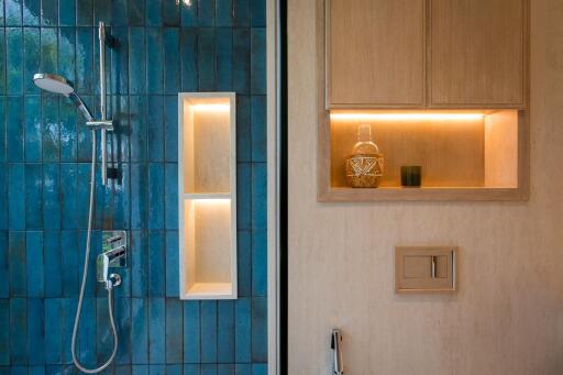 Modern bathroom with blue tiled shower and wooden storage shelves