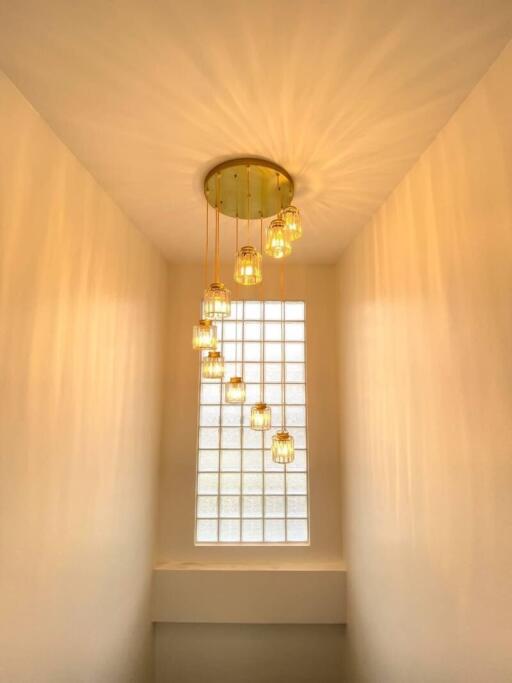 Staircase with modern chandelier and glass block window