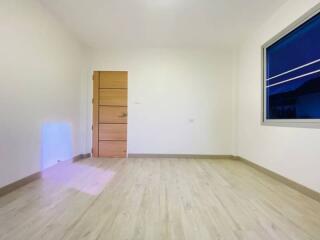 Empty bedroom with wooden door and large window