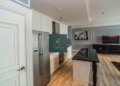 Modern kitchen and living room with stainless steel appliances and flat screen TV