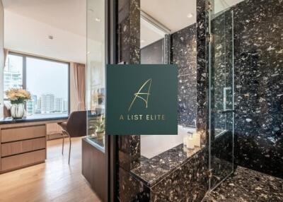 Modern bathroom with marble finishes and a view of the city from the adjacent room