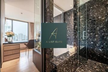 Modern bathroom with marble finishes and a view of the city from the adjacent room