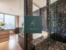 Modern bathroom with marble finishes and a view of the city from the adjacent room