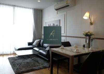 Modern living and dining area with a black leather couch and a dining table setup