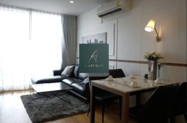 Modern living and dining area with a black leather couch and a dining table setup