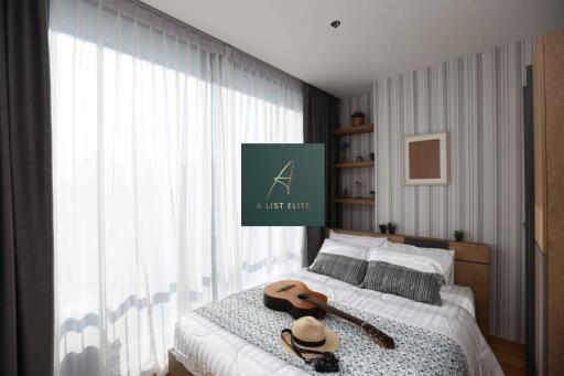 Bedroom with large window, bed, guitar and hat