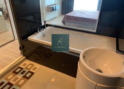 Luxury bathroom with tub and sink, view of bedroom through glass window