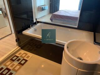 Luxury bathroom with tub and sink, view of bedroom through glass window